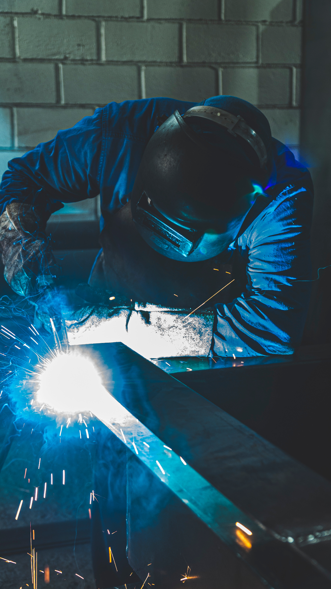 Soldador realizando trabalho de caldeiraria com proteção adequada
